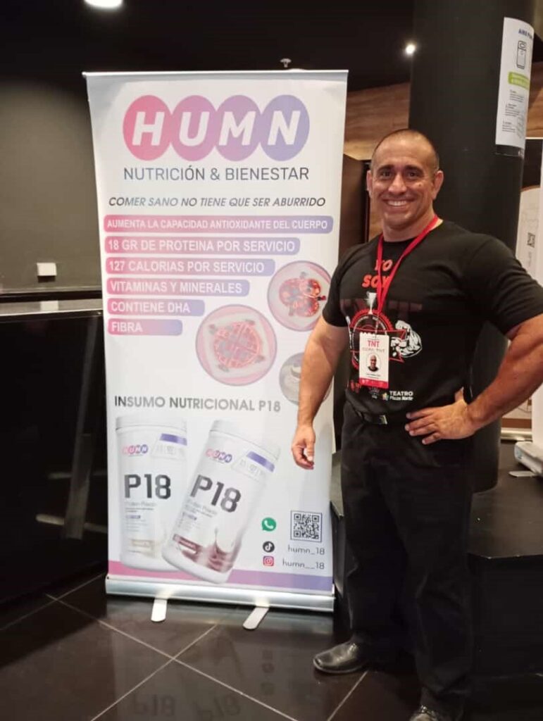 Nuestro fundador posando al costado de banner para información de nuestro productos.